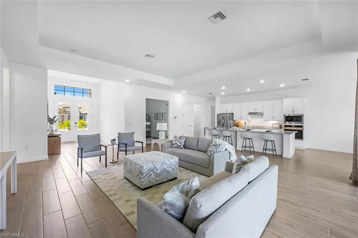 Living room with french doors, light wood-type flooring, and a raised ceiling