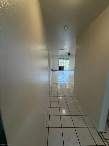 Tiled hallway featuring a neutral color palette, leading to an open-concept living area with recessed lighting and a ceiling fan