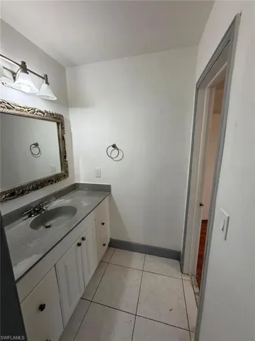 Bathroom vanity with integrated sink, a decorative framed mirror, and a wall-mounted light fixture
