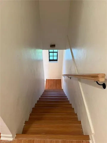 Staircase with wood-finish treads and risers, featuring a natural wood handrail with black metal supports