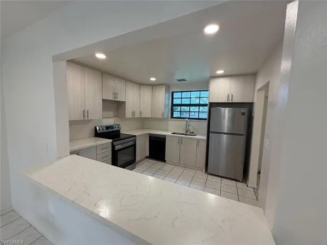 Kitchen featuring light-toned cabinetry with brushed nickel hardware, light-toned countertops, stainless steel appliances, and recessed lighting