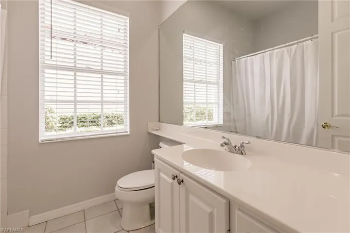 Bathroom with tile patterned floors, toilet, curtained shower, and vanity