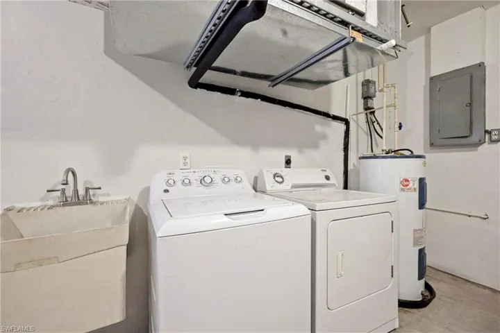 Laundry area featuring washing machine and dryer, electric panel, and water heater