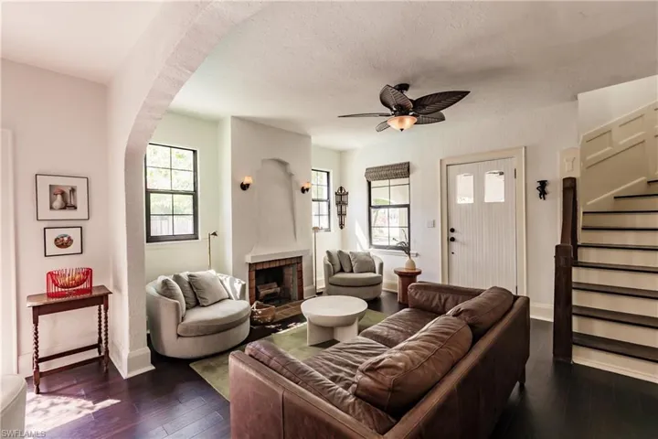 Living room with dark hardwood / wood-style flooring, ceiling fan, a fireplace, and a wealth of natural light