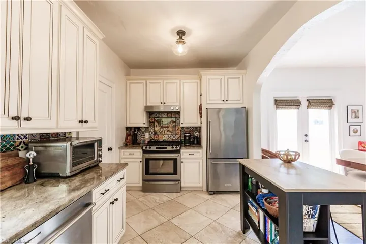 Kitchen with decorative backsplash, dark stone countertops, and stainless steel appliances