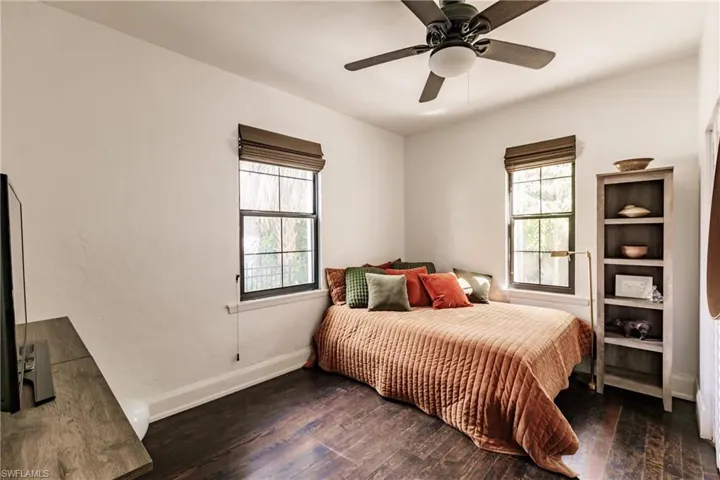 Bedroom with ceiling fan, multiple windows, and dark hardwood / wood-style floors