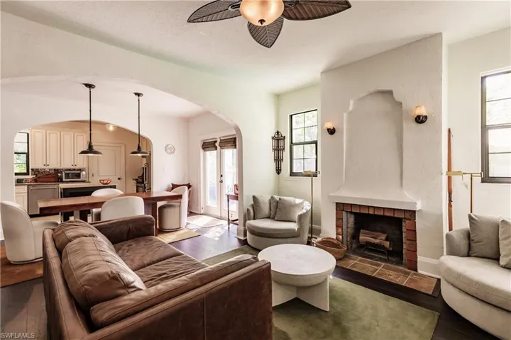 Living room with ceiling fan, a textured ceiling, light wood-type flooring, and a fireplace