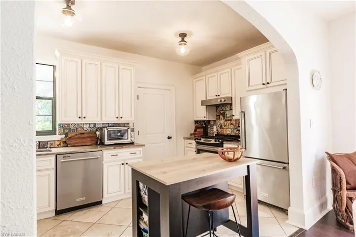 Kitchen featuring light tile patterned flooring, stainless steel appliances, and backsplash