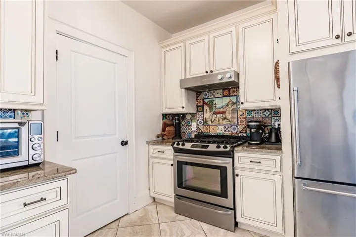 Kitchen with light tile patterned flooring, dark stone countertops, stainless steel appliances, and tasteful backsplash
