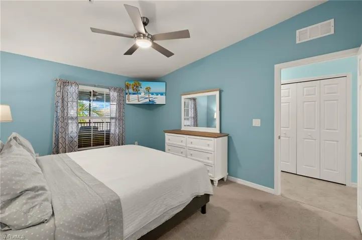 Bedroom featuring vaulted ceiling, baseboards, a ceiling fan, and light carpet