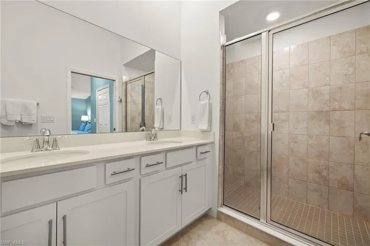 Full bath with a stall shower, double vanity, connected bathroom, and tile patterned floors