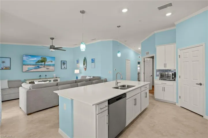 Kitchen with dishwasher, a sink, crown molding, white cabinetry, and an island with sink