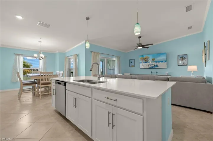 Kitchen featuring dishwasher, a sink, crown molding, open floor plan, and light tile patterned floors