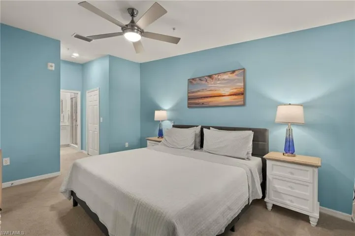 Bedroom with carpet, baseboards, ensuite bath, and ceiling fan