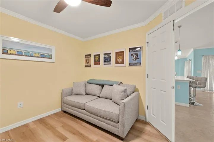 Living area with a ceiling fan, crown molding, baseboards, and wood finished floors