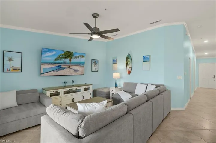 Living room with light tile patterned floors, crown molding, a ceiling fan, recessed lighting, and baseboards