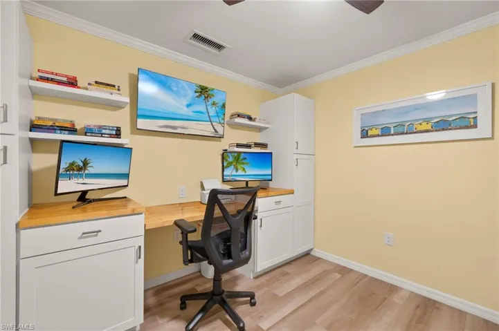 Office featuring built in study area, light wood-type flooring, crown molding, baseboards, and ceiling fan