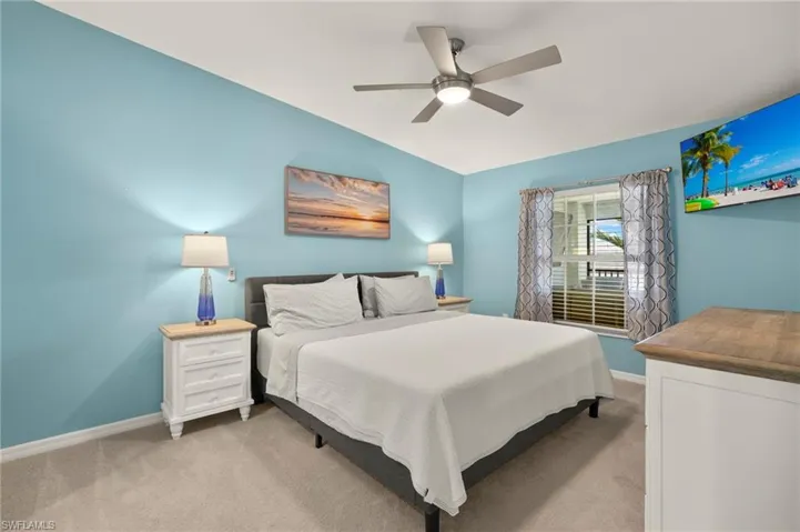 Bedroom with light carpet, baseboards, and a ceiling fan