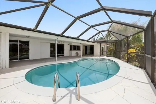 View of pool with a patio area and glass enclosure