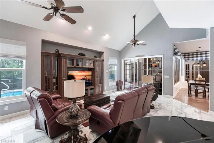 Tiled living room with ceiling fan, french doors, and high vaulted ceiling