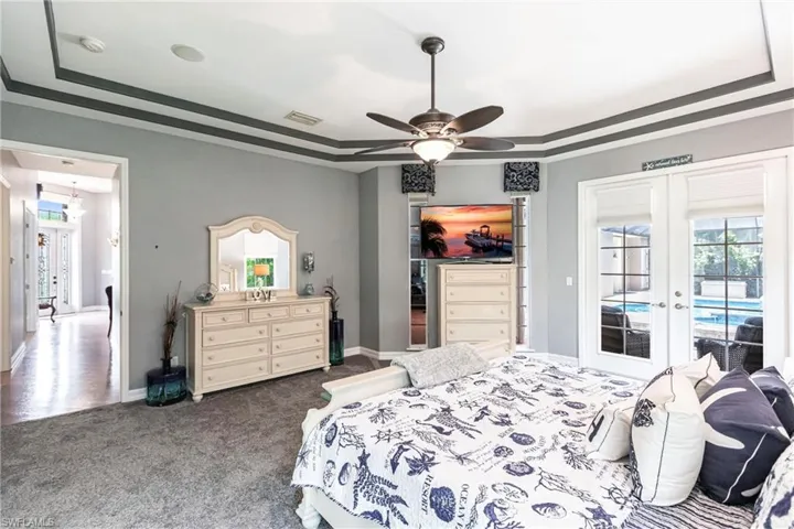 Bedroom featuring access to exterior, ceiling fan, a tray ceiling, carpet floors, and french doors