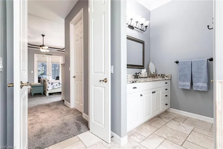 Bathroom with ceiling fan, french doors, ornamental molding, tile patterned flooring, and vanity