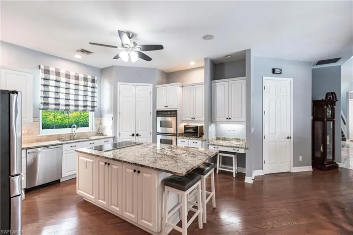 Kitchen featuring appliances with stainless steel finishes, dark wood-type flooring, a kitchen island, and ceiling fan