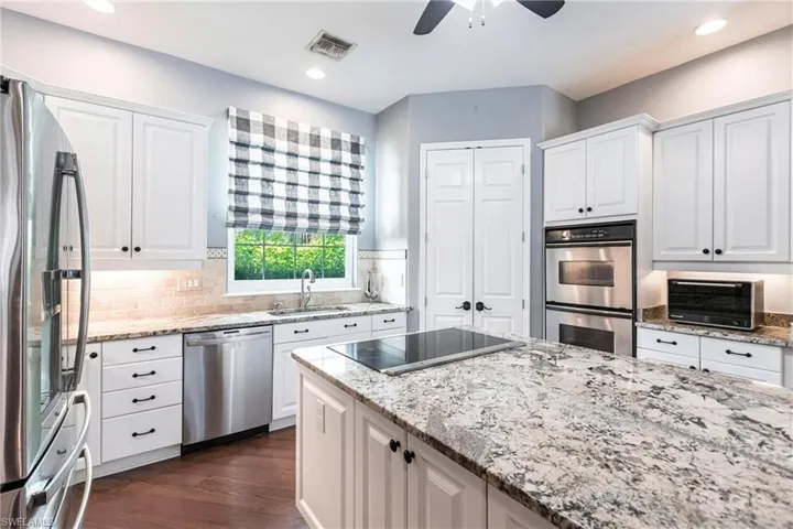 Kitchen with ceiling fan, white cabinetry, appliances with stainless steel finishes, sink, and dark hardwood / wood-style flooring