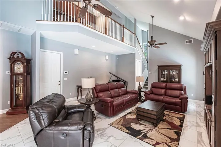 Living room with high vaulted ceiling, light tile patterned floors, and ceiling fan