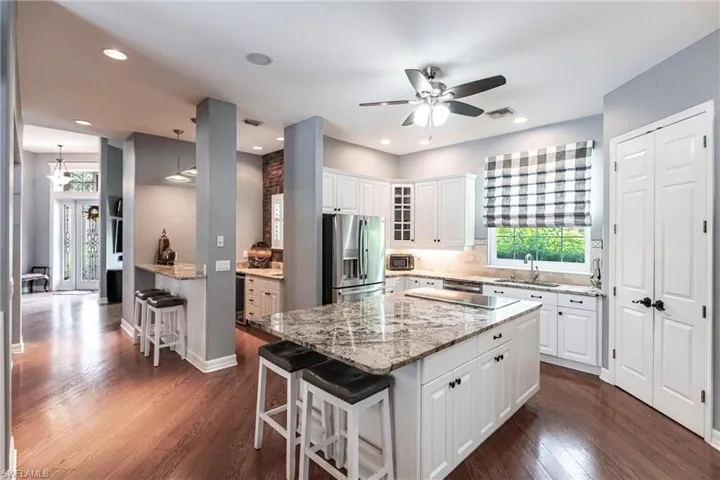 Kitchen with dark hardwood / wood-style floors, stainless steel refrigerator with ice dispenser, white cabinetry, and a kitchen island