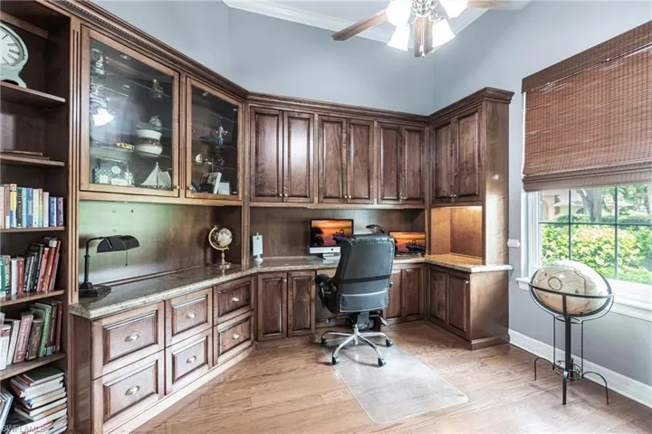 Office area featuring ceiling fan, crown molding, built in desk, and light hardwood / wood-style floors