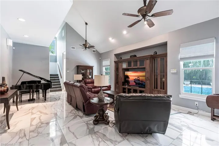 Tiled living room featuring ceiling fan and high vaulted ceiling