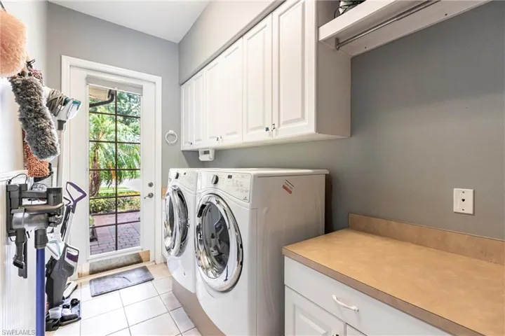 Laundry room with light tile patterned floors, cabinets, and washer and dryer