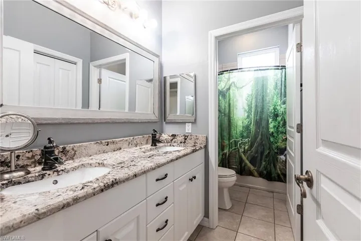 Bathroom featuring tile patterned floors, double vanity, and toilet