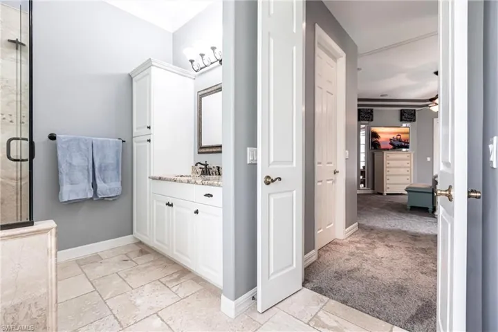 Bathroom with a shower with shower door, crown molding, tile patterned floors, vanity, and ceiling fan