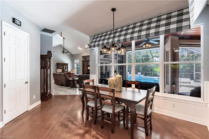 Dining area featuring vaulted ceiling, ceiling fan with notable chandelier, and hardwood / wood-style floors