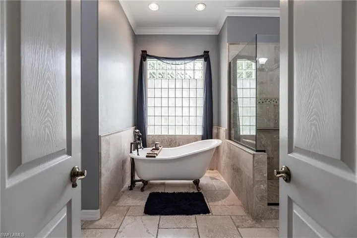 Bathroom with tile patterned floors, tile walls, ornamental molding, and separate shower and tub