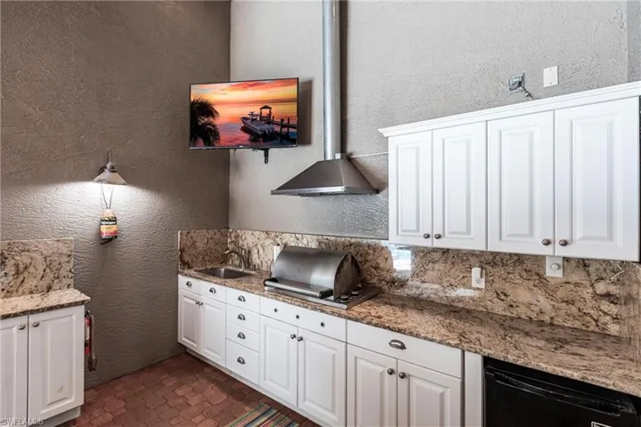 Full outdoor kitchen with propane grill, refrigerator and storage