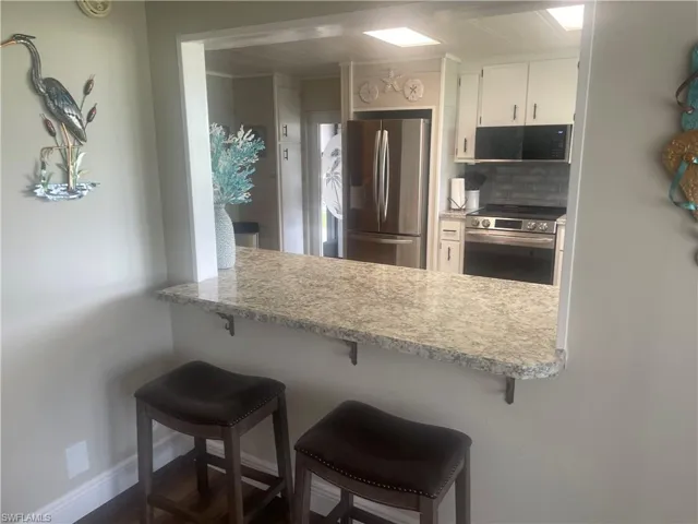 Kitchen pass-through featuring a polished stone countertop and a dark gray subway tile backsplash