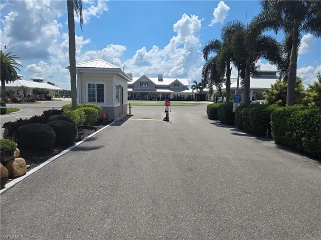 Paved entrance with a guardhouse, mature palm trees, and manicured landscaping
