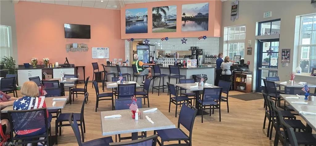 Spacious dining area featuring neutral-toned flooring, ample natural light from multiple windows, and a prominent service counter with bar seating