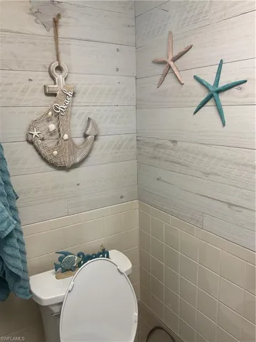 Bathroom featuring white plank wall paneling and a ceramic tiled lower wall