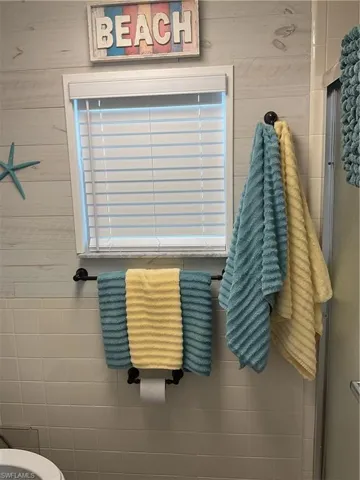 Bathroom showcasing a window with blinds, a black metal towel bar, and a black wall hook