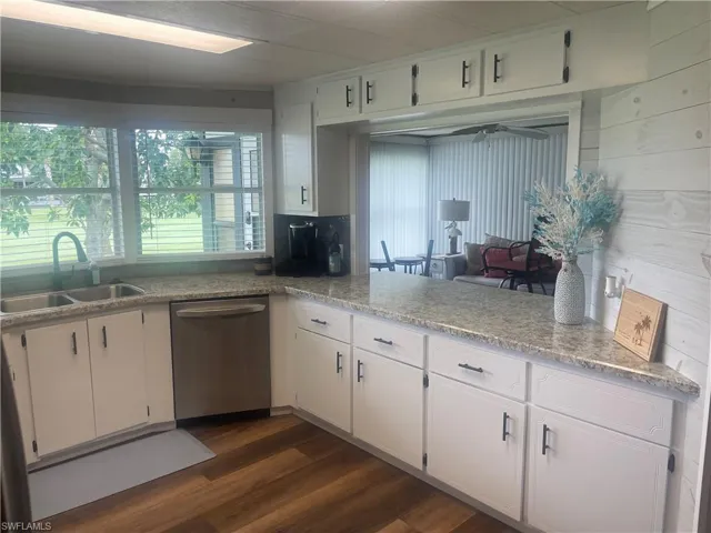 Kitchen featuring white cabinetry with dark hardware, speckled countertops, and a double basin sink with a gooseneck faucet