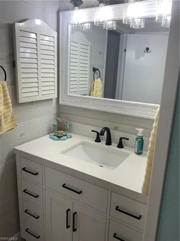 Bathroom vanity featuring a white countertop, undermount sink, and matte black faucet