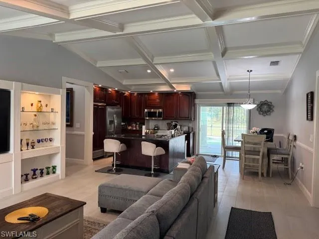 Living room featuring light hardwood / wood-style floors, ornamental molding, and beamed ceiling