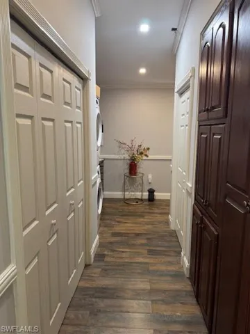 Hallway with ornamental molding and dark wood-type flooring