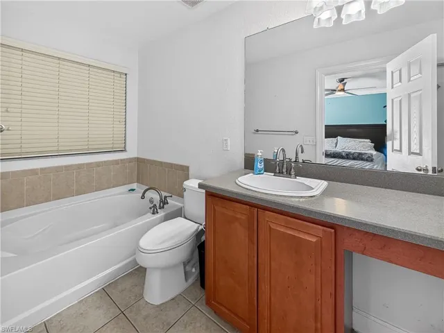 Bathroom with a garden tub, vanity, light tile patterned flooring, connected bathroom, and a ceiling fan