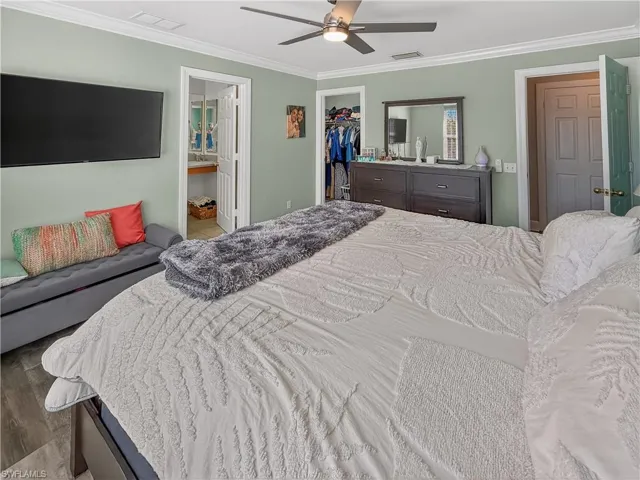Bedroom with crown molding, a ceiling fan, wood finished floors, and a spacious closet