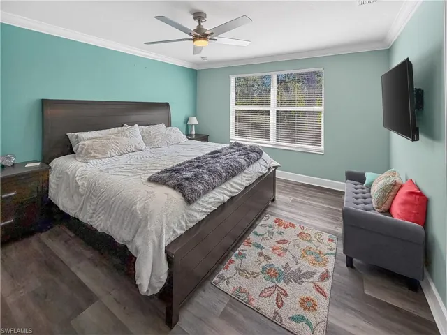 Bedroom featuring wood finished floors, ornamental molding, and a ceiling fan